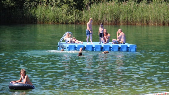 Menschen sonnen sich auf einer Plattform in einem Badesee. © NDR Foto: Andreas Barnickel