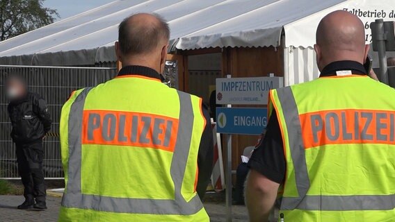 Zwei Polizisten stehen während einer Razzia vor einem Zelt des Impfzentrums in Schortens. © TeleNewsNetwork 