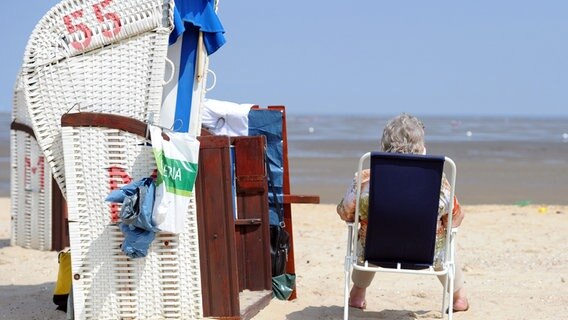 Eine Urlauberin sitzt vor ihrem Strandkorb an einem Strand in Cuxhaven. © dpa-Bildfunk Foto: Caroline Seidel