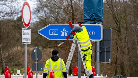 Ein rotes Kreuz wird über dem Autobahnschild der A27 angebracht. © dpa Foto: Sina Schuldt