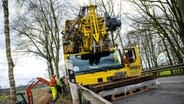 Ein verunglückter Kranwagen blockiert eine Kreisstraße, über die eine Umleitung für die gesperrte A27 führt. © dpa Foto: Sina Schuldt