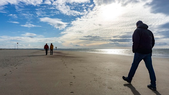 Spaziergänger sind am Strand von Spiekeroog unterwegs. © picture alliance/Jochen Tack Foto: Jochen Tack
