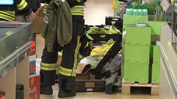 Feuerwehrleute durchsuchen Bananenkisten in einem Supermarkt. © Nord-West-Media TV 