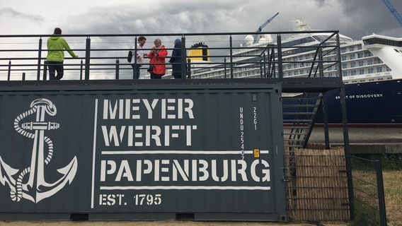 Menschen stehen auf einem Treppengerüst mit der Aufschrift "Meyer Werft Papenburg". © NDR Foto: Oliver Gressieker