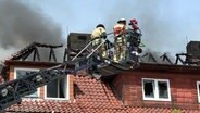 Feuerwehrleute löschen mit einer Drehleiter ein brennendes Gebäude in Stadland. © Nord-West-Media TV 