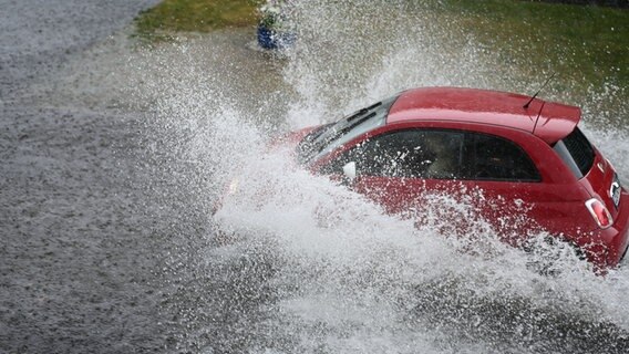 Ein Auto fährt auf einer überfluteten Straße. © dpa-Bildfunk +++ Foto: Lars Klemmer/dpa