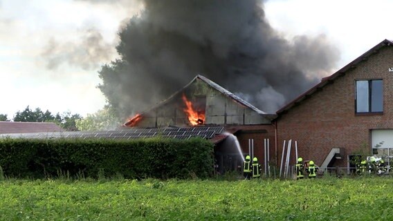 Einsatzkräfte der Feuerwehr löschen einen Brand an einer Lagerhalle. © Nord-West-Media TV 