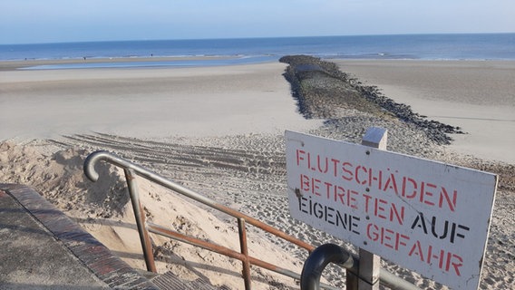 Ein Schild warnt an einem Strand auf Wangerooge vor Flutschäden. Darauf steht "Betreten auf eigene Gefahr". © dpa-Bildfunk 