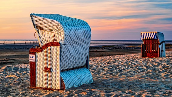 Strandkörbe stehen im Sonnenuntergang in Sahlenburg bei Cuxhaven am Strand. © picture alliance / Zoonar | THOMAS RIESS Foto: THOMAS RIESS