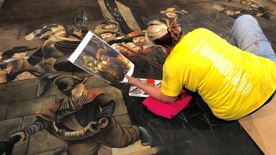 Die Künstlerin Julie Purcell aus den USA arbeitet beim Street Art Festival in Wilhelmshaven an einer Replik des Gemäldes "Die Nachtwache" von Rembrandt. © NDR Foto: Jutta Przygoda