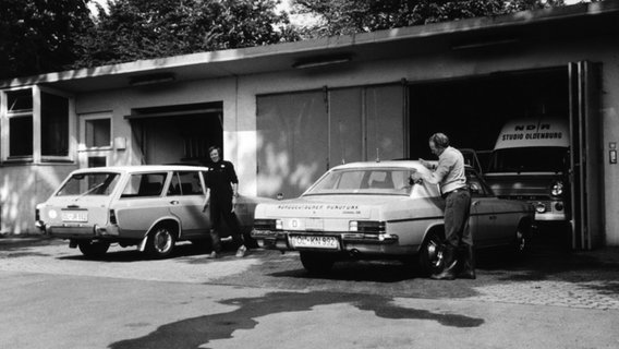 Zwei Männer waschen Autos vor einer Garage. © NDR 