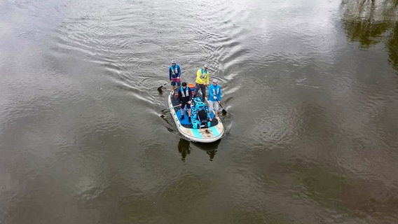 Vier Männer stehen auf einem Standup-Paddel-Board und fahren damit auf einem Fluss. Vier Männer stehen auf einem Standup-Paddel-Board und fahren damit auf einem Fluss. © Matthias Buse