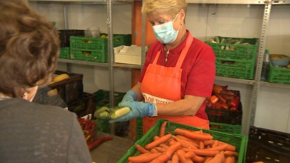 Menschen holen Lebensmittel bei einer Ausgabe der Tafeln. © NDR 