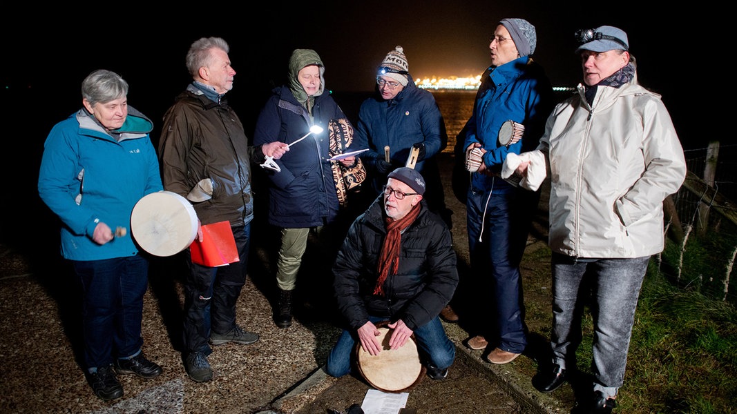 Hooksiel: Mehrere Umweltschützer singen und trommeln im Außenhafen von Hooksiel vor dem LNG-Terminal in der Nordsee. 