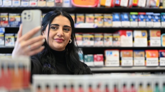 Esra Cayir, die als "Tankstellenlady" auf Tiktok 1,8 Millionen Follower hat, steht in der Tankstelle und filmt sich mit einem Smartphone. © Lars Klemmer/dpa Foto: Lars Klemmer