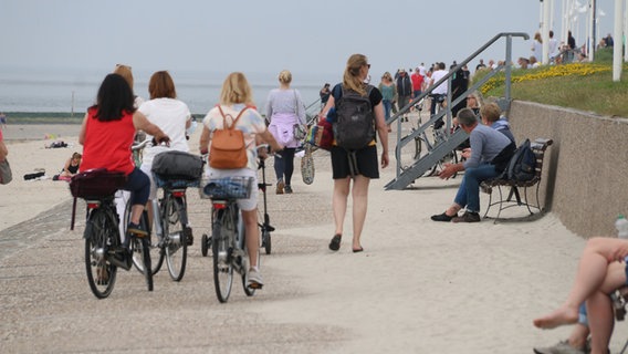 Menschen spazieren an einer Strandpromenade. © picture alliance/dpa Foto: Volker Bartels