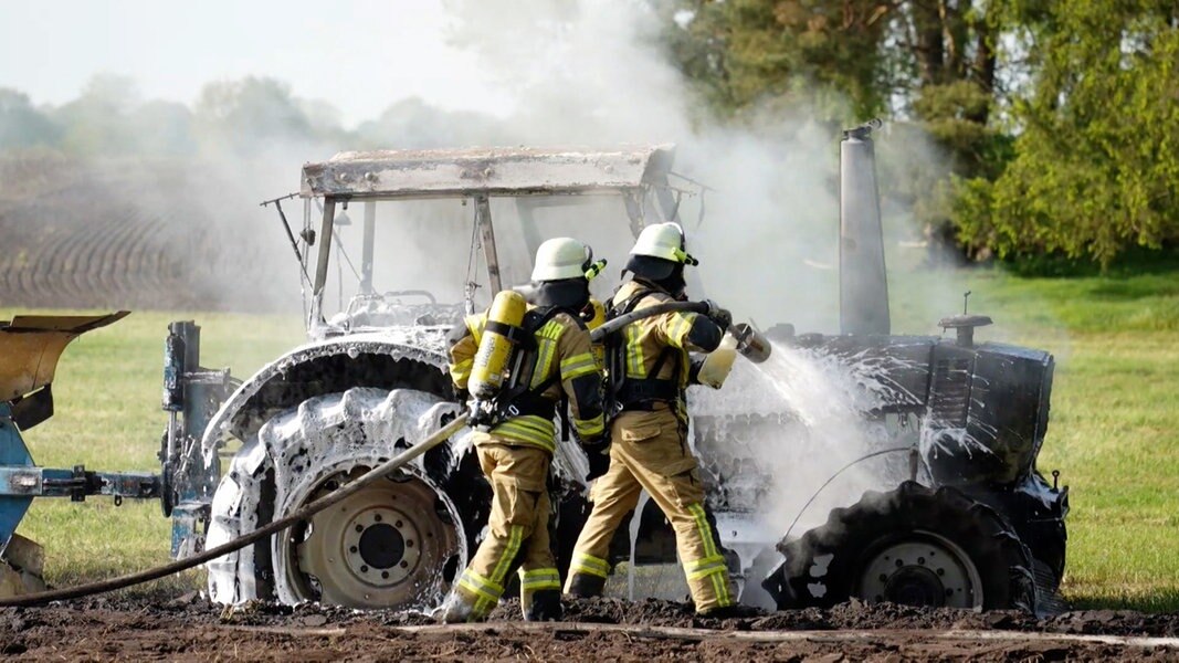 Feuerwehrleute versuchen einen ausgebrannten Traktor in Groß Ippener zu löschen.