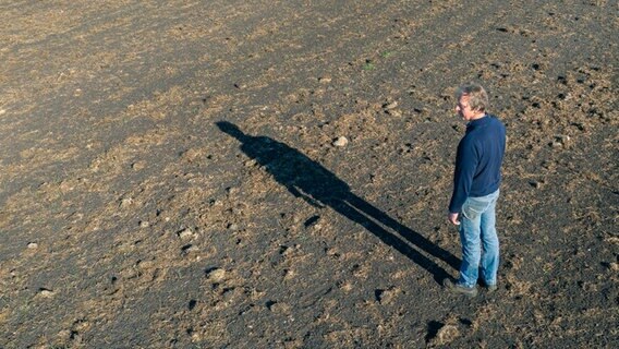 Ein Landwirt steht auf einem vertrockneten Acker in Rastede. © picture alliance/dpa Foto: Mohssen Assanimoghaddam