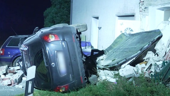 Ein stark zerstörtes Auto liegt neben einem stark beschädigten Wohnhaus. © TeleNewsNetwork 