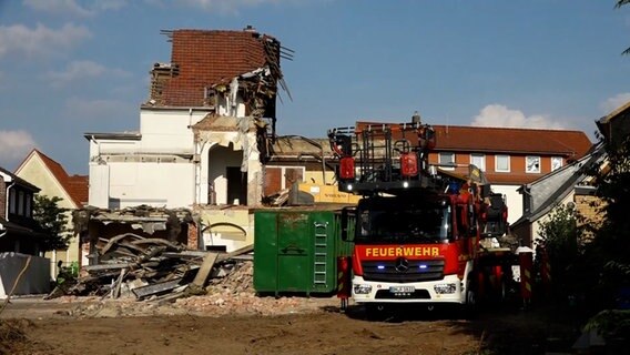 Ein teilweise abgerissenes Haus. Davor ein Feuerwehrwagen. © X 