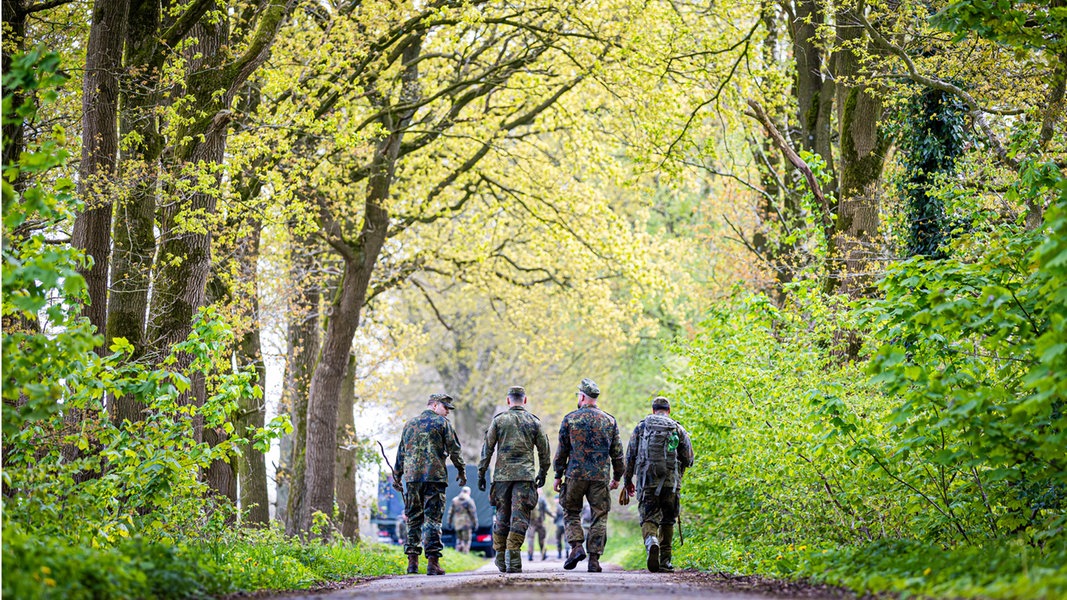 Einsatzkräfte der Bundeswehr laufen einen Waldweg lang.