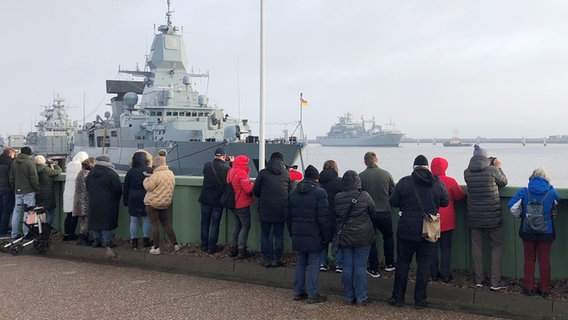 Der Einsatzgruppenversorger "Frankfurt am Main" (hinten rechts) wird von Menschen in Wilhelmshaven begrüßt. © NDR Foto: Jutta Przygoda