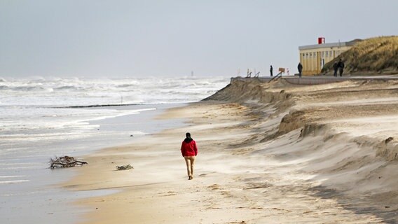 Eine Person geht am Strand von Wangerooge spazieren. © dpa - Bildfunk Foto: Peter Kuchenbuch-Hanken