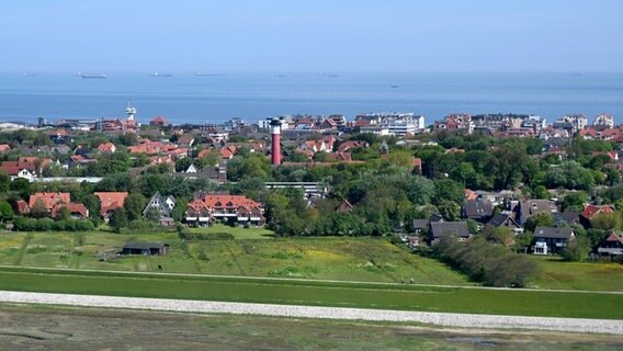 Auf dem Bild zu sehen ist der Ortskern der Gemeinde Wangerooge mit dem alten Leuchtturm. Im Hintergrund fahren Frachter auf der Nordsee. © picture alliance / Hauke-Christian Dittrich Foto: Hauke-Christian Dittrich