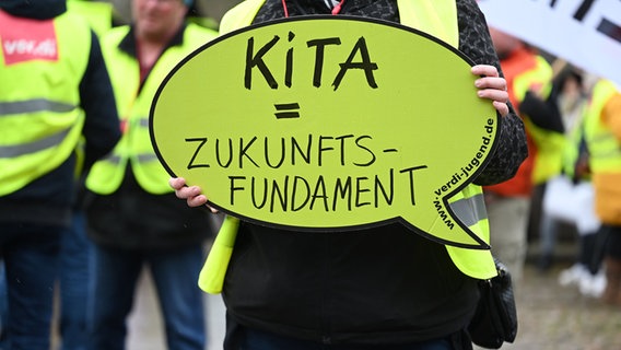 Mężczyzna trzyma tabliczkę z odczytem podczas strajku ostrzegawczego "Kita = przyszły fundament" Wysoki.  © Image Alliance/dpa Zdjęcie: Lars Klemmer