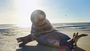 Ein Mensch in einem Robbenkostüm im Wattenmeer © win win Film 