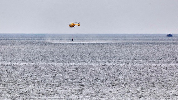 Ein Hubschrauber zieht in Butjadingen zwei Menschen aus dem Wasser. © dpa Foto: Nils Kernbach