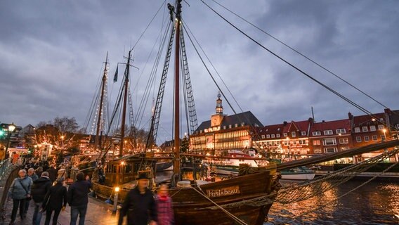 Weihnachtsstimmung auf dem Emder Engelkemarkt - Besucher des Weihnachtsmarktes bummeln an den festlich beleuchteten Schiffen am Ratsdelft entlang. © picture alliance/dpa | Karsten Klama Foto: Karsten Klama