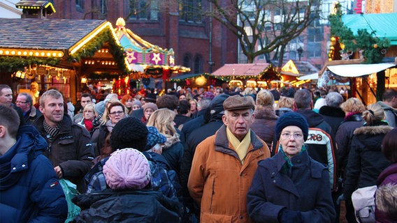 Viele Personen auf einem Weihnachtsmarkt zwischen beleuchteten Ständen. © NDR Foto: Oliver Gressieker