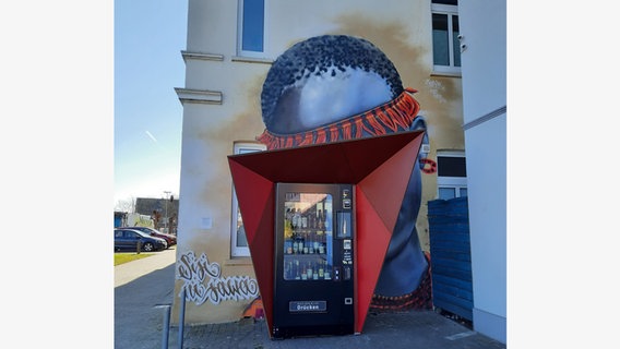 Die „Wein-Box“, ein Automat an dem Weinflaschen verkauft werden, steht vor einem Graffiti in Oldenburg. © Stadt Oldenburg 