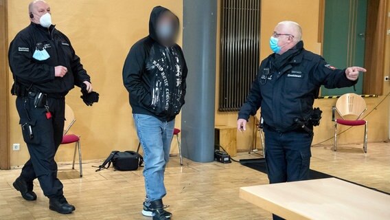 Ein Angeklagter wird vor einem Prozessbeginn in die Stadthalle Verden geführt. © picture alliance Foto: Sina Schuldt