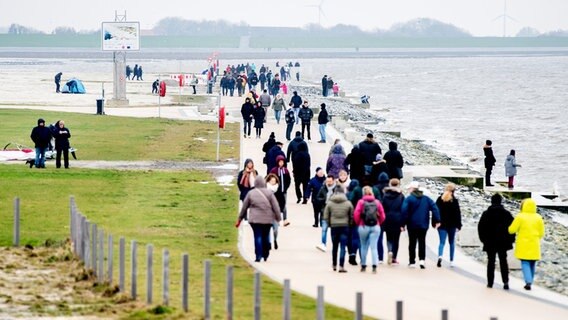 Zahlreiche Spaziergänger sind bei trübem Wetter auf der Promenade am Strand unterwegs. © picture alliance Foto: Hauke-Christian Dittrich