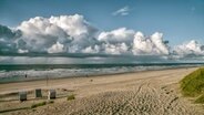 Auf Norderney sind über der Nordsee Wolken zu sehen, im Vordergrund vereinzelt Strandkörbe. © NDR Foto: Joachim Trettin