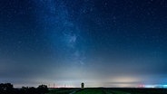 Ein Leuchtturm steht unter einem leuchtenden Sternenhimmel. © NDR Foto: Lorenz Wodzinski