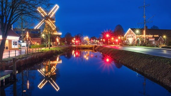 Im Wasser spiegelt sich eine weihnachtlich beleuchtete Windmühle. © NDR Foto: Ralf Claassen