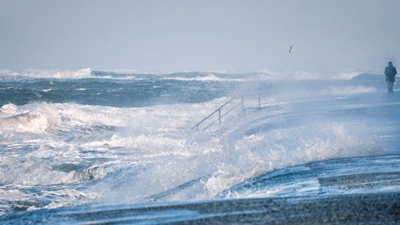 Eine Person geht bei Sturm am Strand von Norderney spazieren. © NDR Foto: Martin Pohl