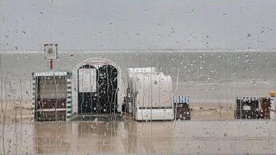 Ein Blick durch eine verregnete Scheibe auf Strandkörbe. © NDR Foto: Heike Scheibe