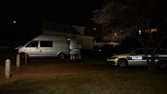 Beamte der Polizei stehen in weißen Schutzanzügen vor einem Wohnhaus. © Nord-West-Media TV 