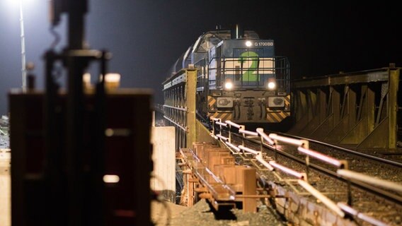 Ein Güterzug fährt in der Nacht über eine Eisenbahnbrücke. © Picture Alliance Foto: Mohssen Assanimoghaddam