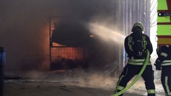 Einsatzkräfte der Feuerwehr löschen einen Brand in einer Lagerhalle. © NonstopNews 