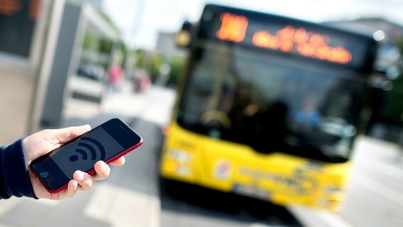 Ein Smartphone mit WLAN-Symbol vor einem Linienbus. © dpa-Bildfunk Foto: Hauke-Christian Dittrich