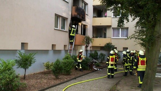 Feuerwehrleute stehen vor dem Balkon einer Wohnung im Wollepark in Delmenhorst, in der es gebrannt hatte. © Nonstop News 