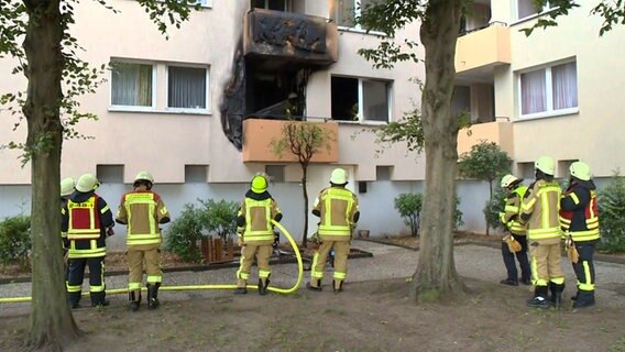 Feuerwehrleute stehen vor dem Balkon einer Wohnung im Wollepark in Delmenhorst, in der es gebrannt hatte. © Nonstop News 