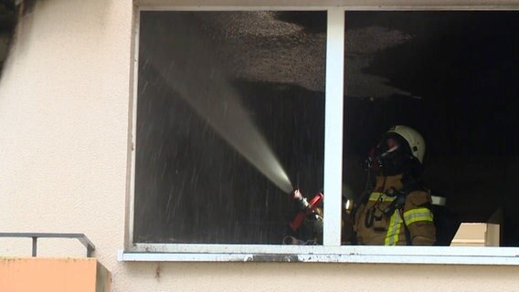 Ein Feuerwehrmann löscht den Brand in einer Wohnung im Delmenhorster Wollepark. © Nonstop News 