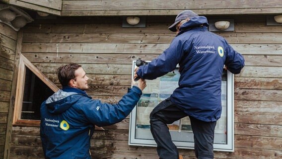 Zwei Nationalpark-Ranger beim Ausstatten einer Infohütte. © Lukas Lehmann Foto: Lukas Lehmann