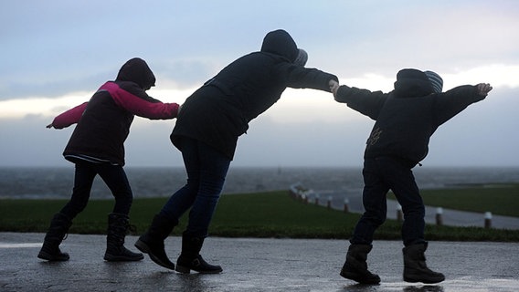 Drei Personen stemmen sich gegen den Wind. © dpa-Bildfunk Foto: Ingo Wagner